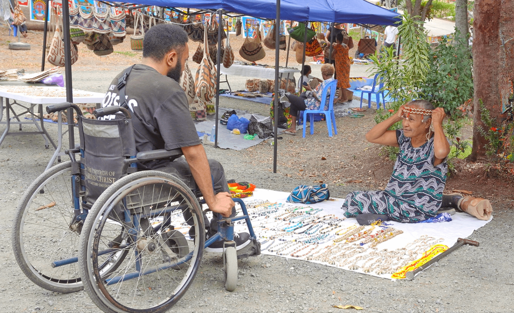 Samuel Rei at the craft market with vendor Hera Toi – a woman with a disability from Pari village. Hera is a regular vendor at the Moresby Arts Theatre craft market.